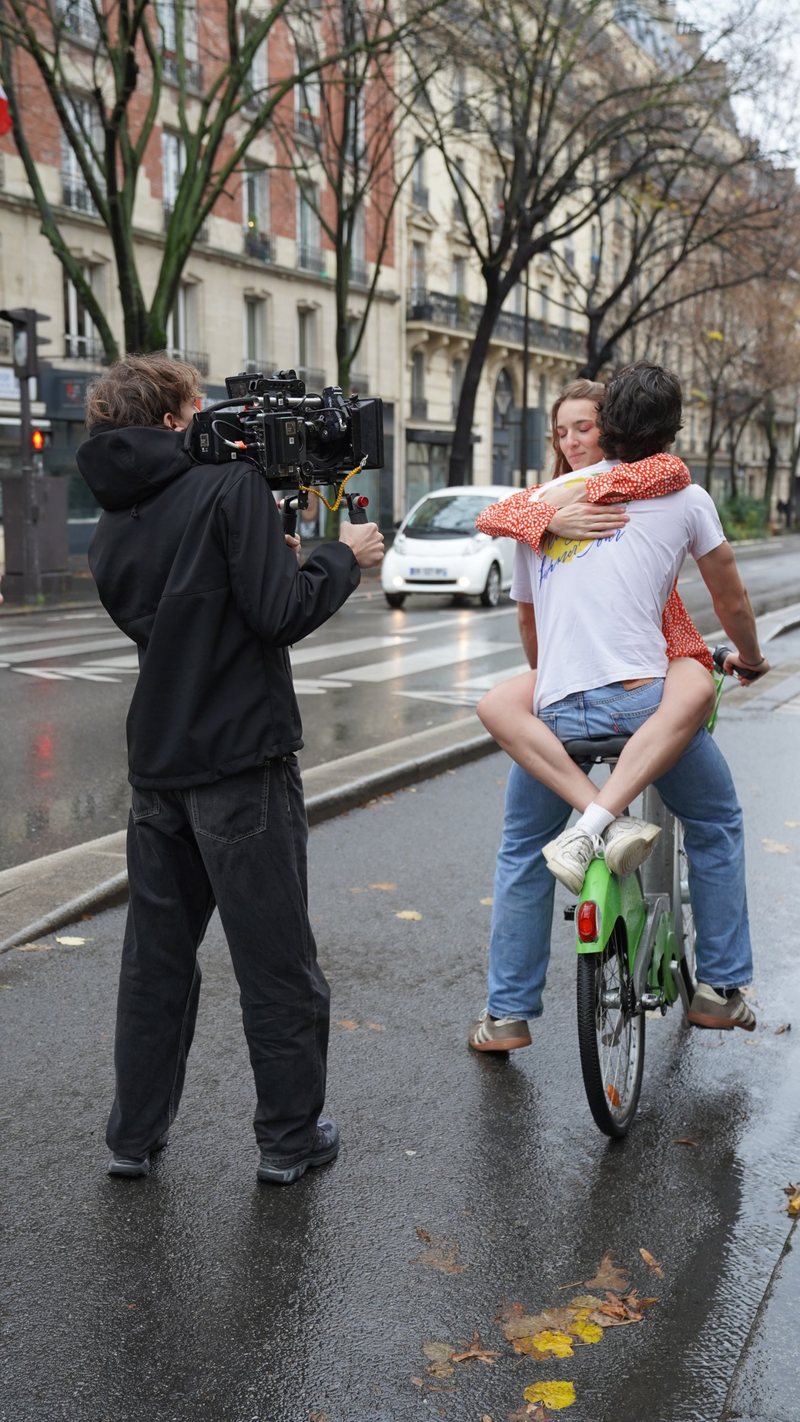 Tournage dans une rue de Paris, avec un cadreur et deux comédiens